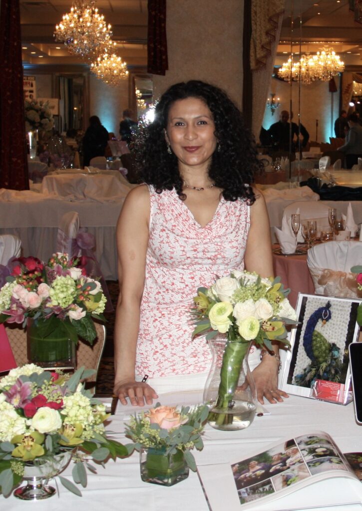 Mayuri, home based studio florist at a bridal show with fresh floral arrangement.