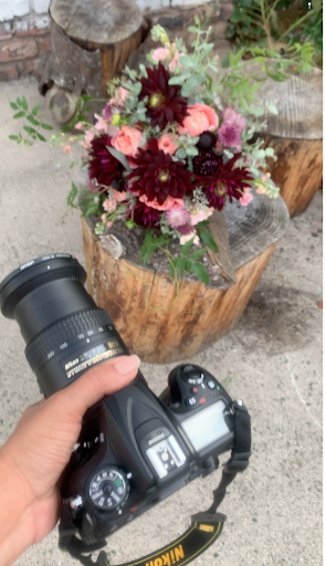 A florist Photographing floral designed work in natural light in the early morning with a professional camera